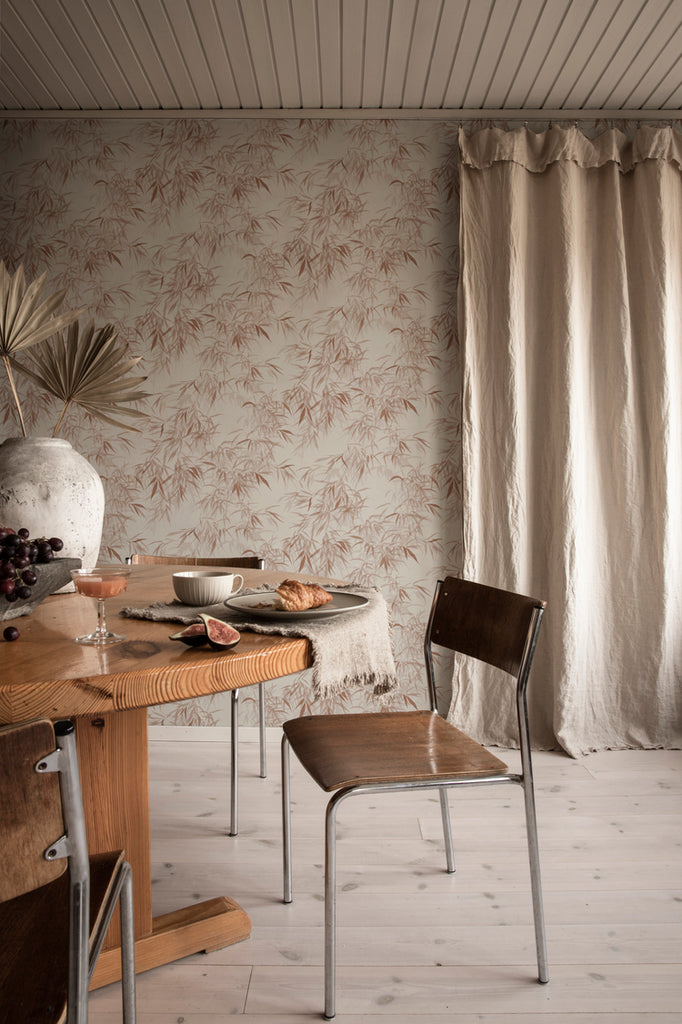 Jon Watercolor Bamboo Japanese Wallpaper in Terracotta featured on a wall a dining area with wooden table and chair with beige curtain on the background