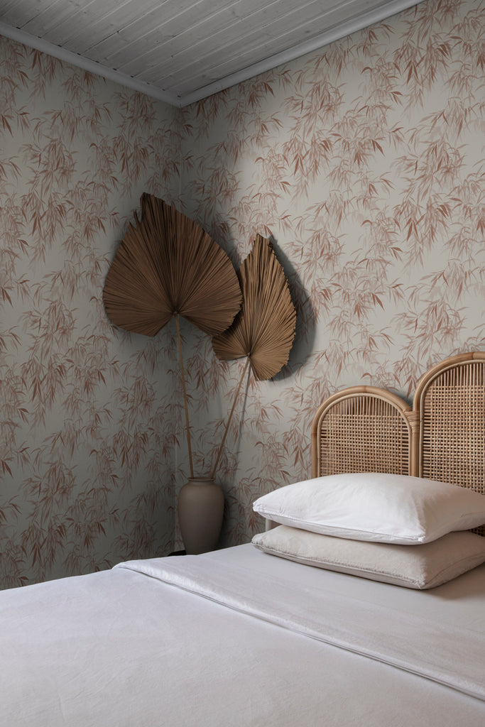Jon Watercolor Bamboo Japanese Wallpaper in Terracotta Featured on a wall of a bedroom with a bed that has rattan frame, white bed sheets, and white pillows