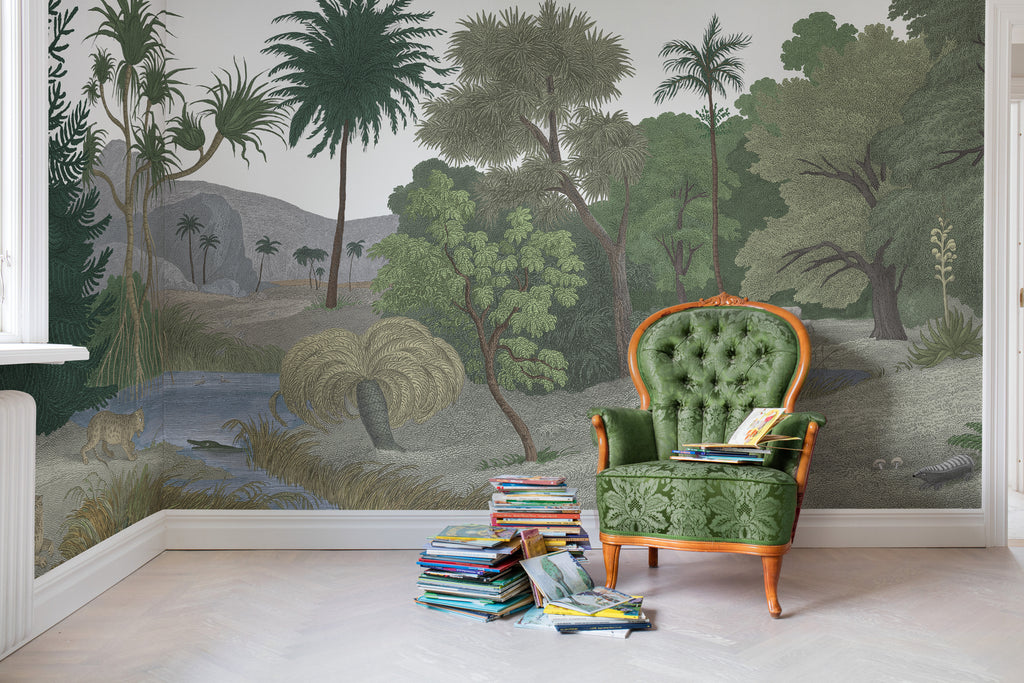 Jungle Land, Mural Wallpaper in forest green featured on a wall of a room with a green sofa and stacked books