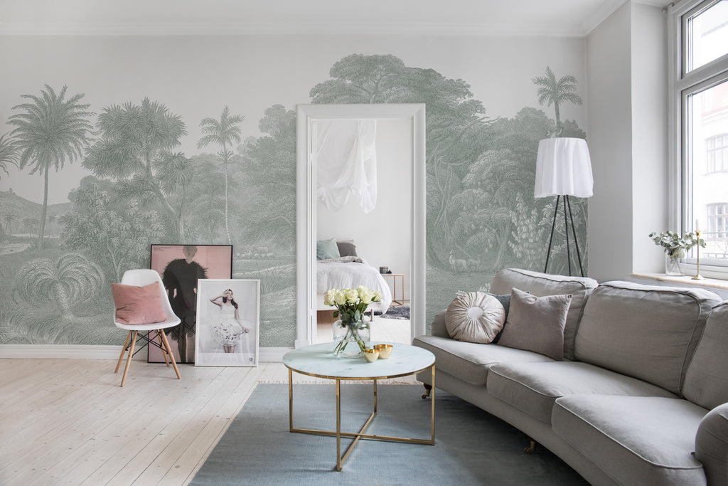 Jungle Land, Mural Wallpaper in Light Grey featured on a wall of a living area with grey sofa and round table with a vase of flowers