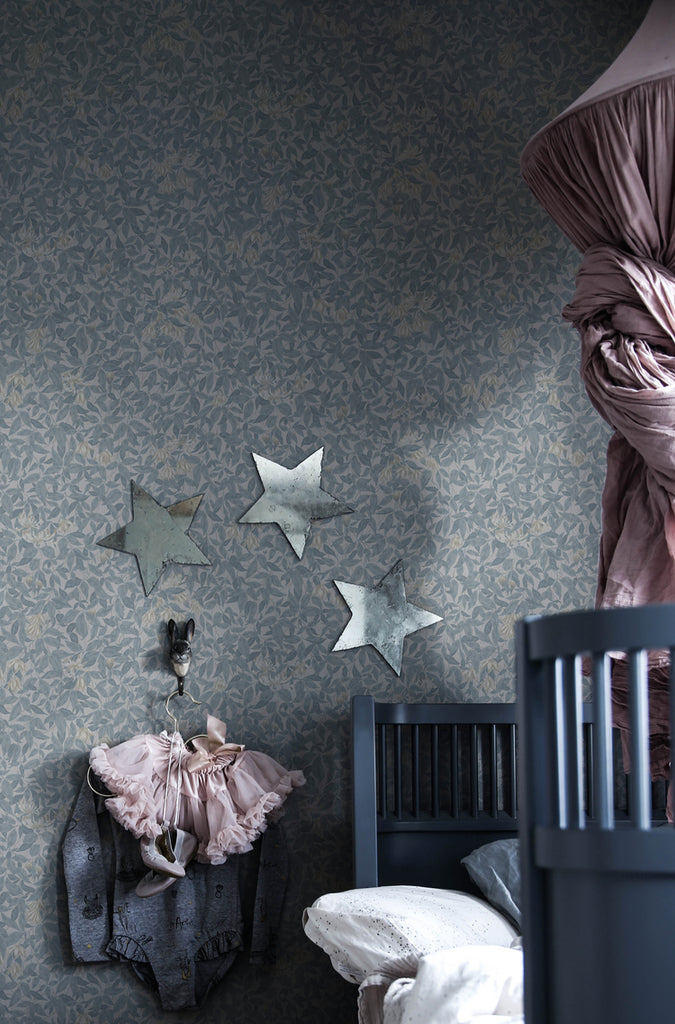 Linnea, Floral Pattern Wallpaper in blue featured on a wall of a kid’s room with grey crib and stars on the wall 