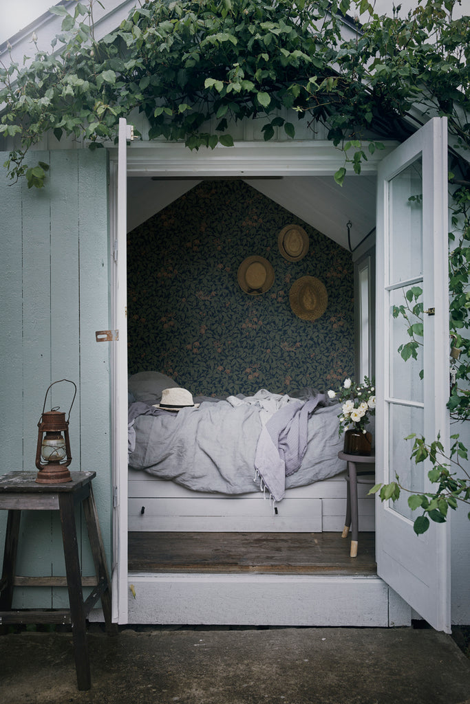 Linnea, Floral Pattern Wallpaper in dark blue featured on a wall of a kid’s mini house room as seen from its white wooden doors