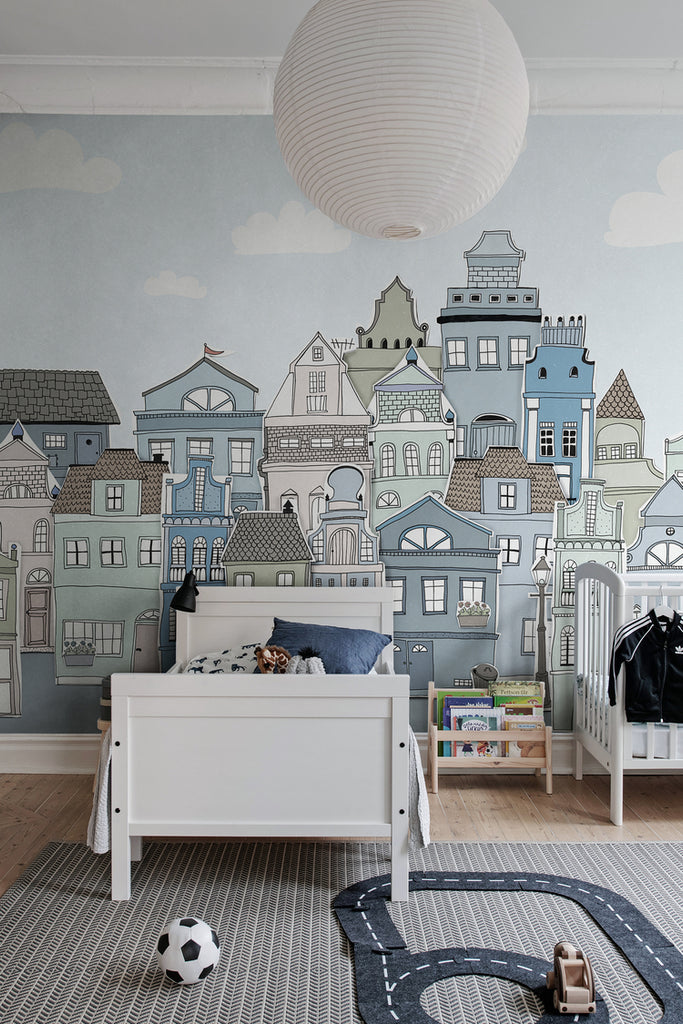 London Houses, Mural Wallpaper in blue featured on a wall of a kid’s room with toys and white bed frame