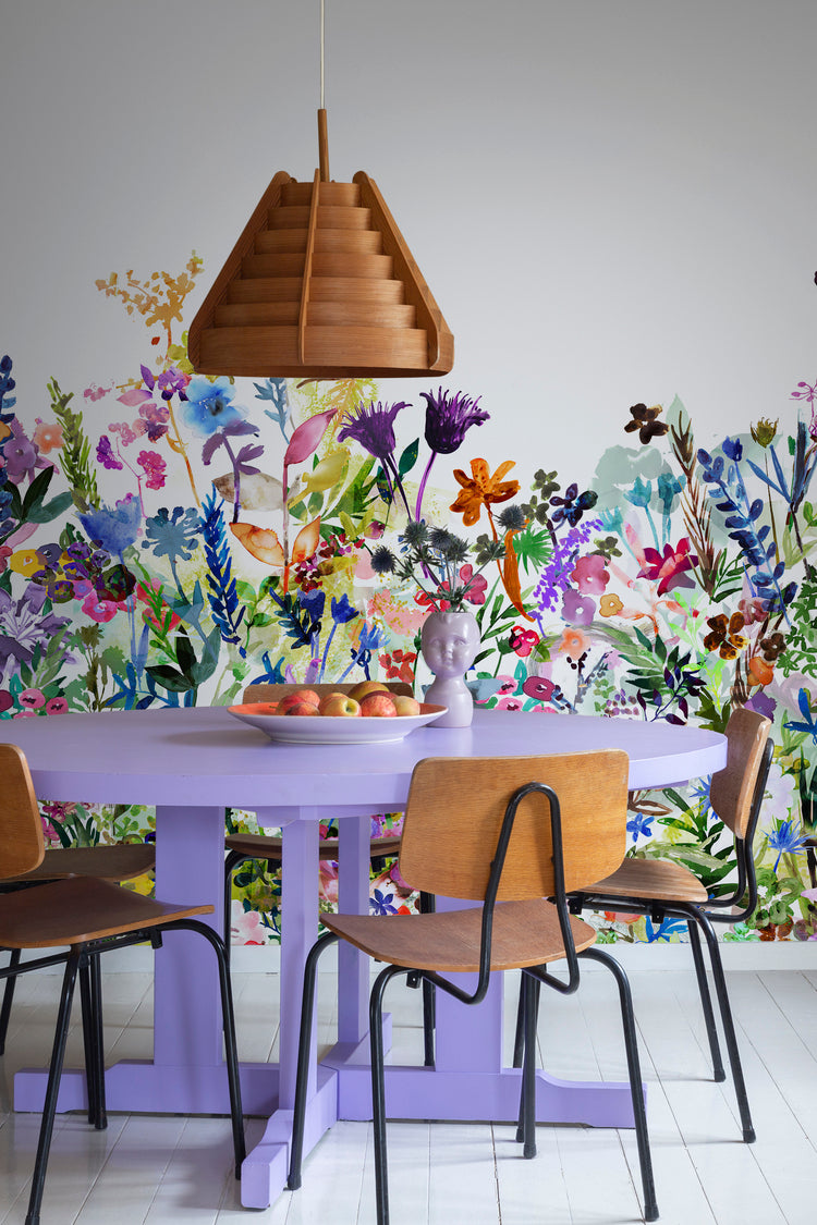May Meadow, Floral Mural Wallpaper in multicolor bright featured on a wall of a dining area with violet round table and wooden chair