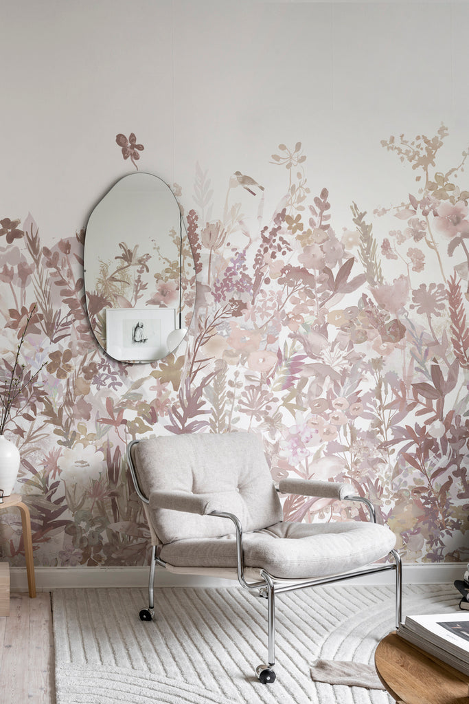 May Meadow, Floral Mural Wallpaper in soft pink featured on a wall of a room with a single sofa chair and a mirror on the wall with a white floor mat