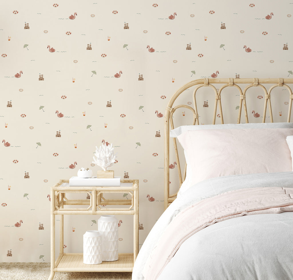 A rattan nightstand, decorated with a small white vase and a few ceramic pieces, complements the matching headboard and frame of the bed. The neutral tones of the furniture blend seamlessly with Mini Beach Day, Pattern Wallpaper in Sand, creating a relaxing and airy atmosphere in the room.