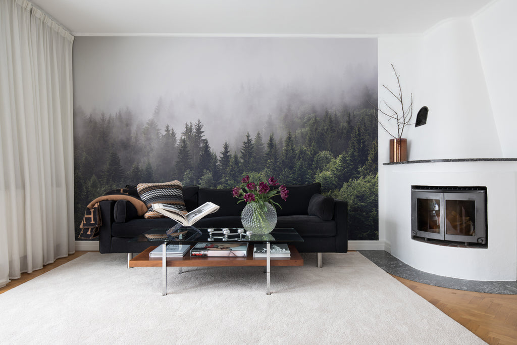 Misty Fir Woods, Landscape Mural Wallpaper featured on wall of a living area with black sofa and brown coffee table