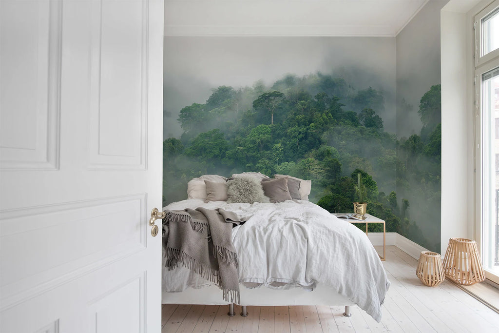 Misty Jungle, Landscape Mural Wallpaper featured on a wall of a bedroom with white bedsheets and grey pillows