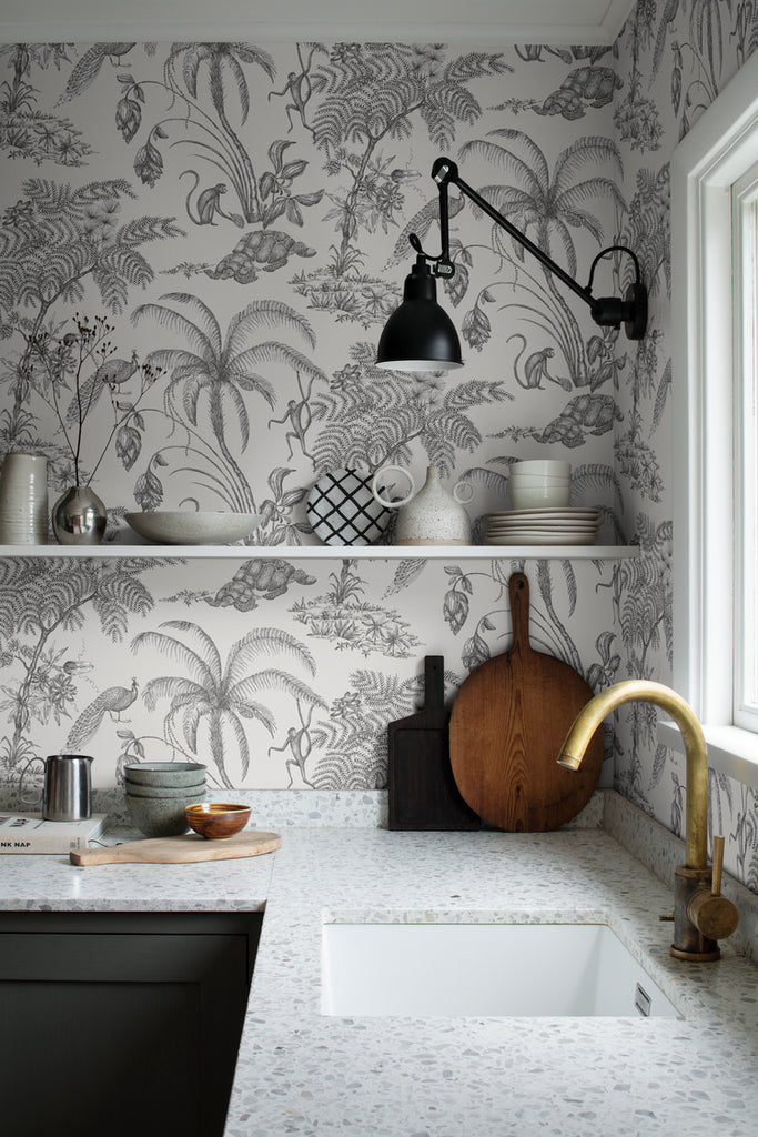 Moa, Tropical Pattern Wallpaper in dark grey featured on a wall of a kitchen with white granite finish on the countertop and ceramic kitchen wares
