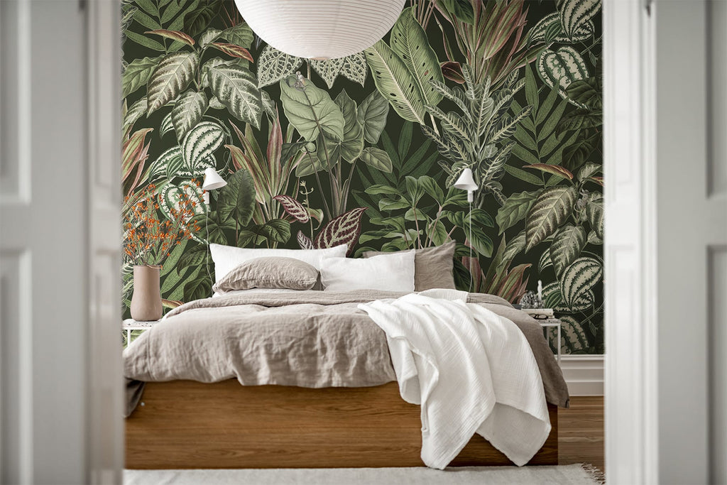 Night-time Jungle, Tropical Mural Wallpaper in forest green featured on a wall of a bedroom with a bed with white and light brown sheets 
