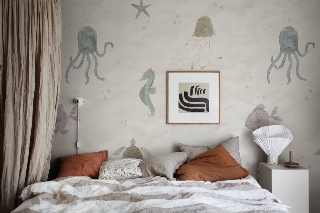 Ocean Friends, Pattern Wallpaper in sand featured on a wall of a bedroom with multicolored pillows and a patterned sheets