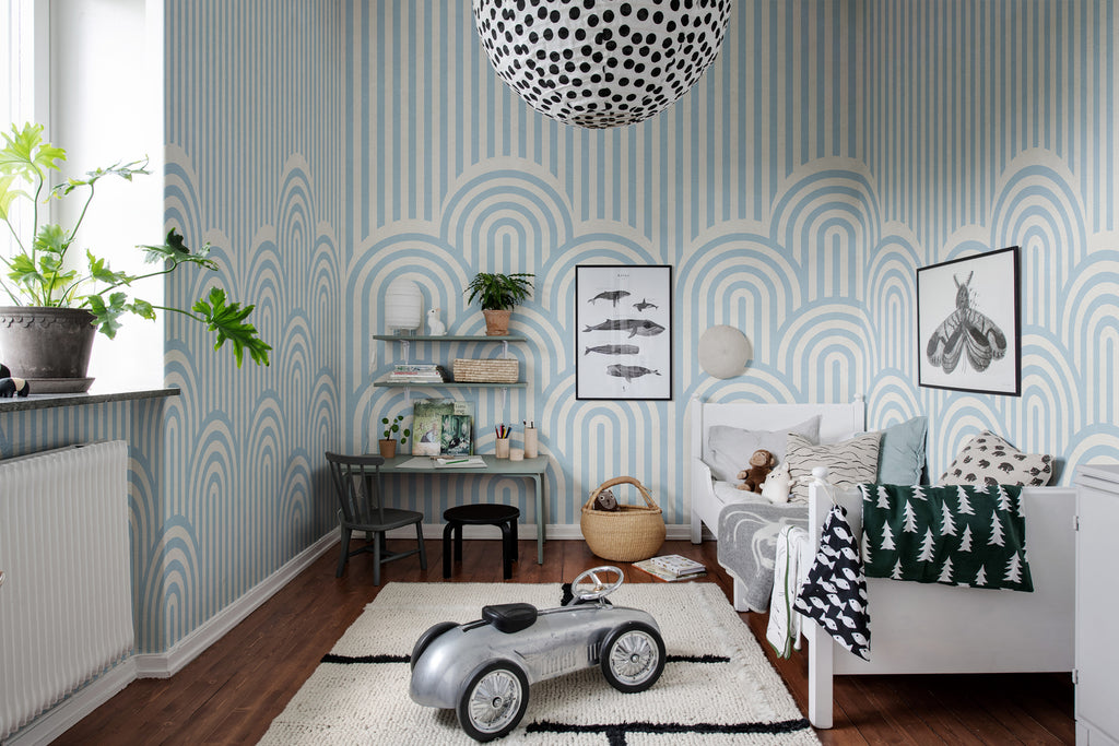 On the Dunes, Geometric Wallpaper in Light Blue featured on a kids’ bedroom with grey sheets and a grey toy car with white floormat