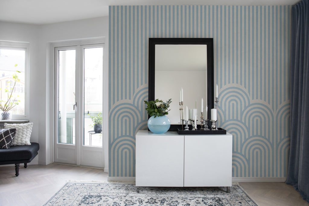 On the Dunes, Geometric Wallpaper in Light Blue featured on a hallway with a vanity area with black mirror and white cabinetry with a vase and candles on top