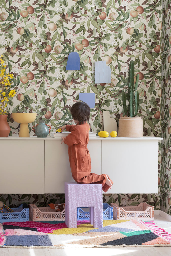 Peach Valley, Floral Pattern Wallpaper in the colourway of Honey, seen in a kid's playroom with colorful vases and furniture