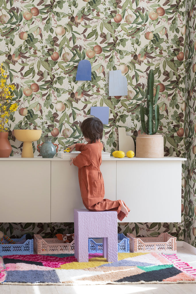 Peach Valley, Floral Pattern Wallpaper in the colourway of Honey, seen in a kid's playroom with colorful vases and furniture