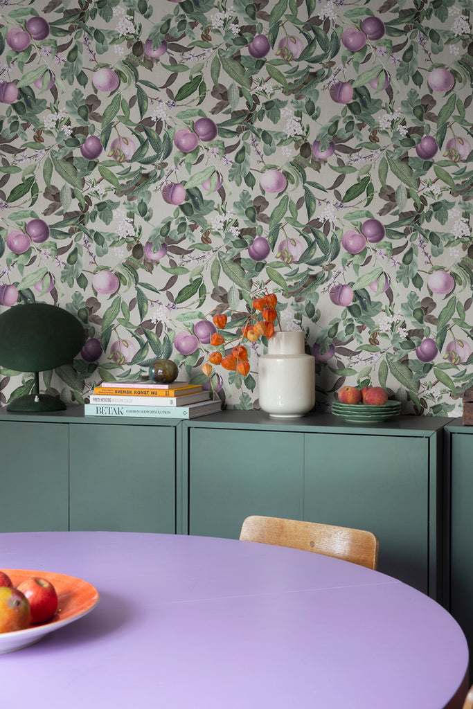 Peach Valley, Floral Pattern Wallpaper in plum, featured in a dining area with a drawer full of books on top and violet dining table.
