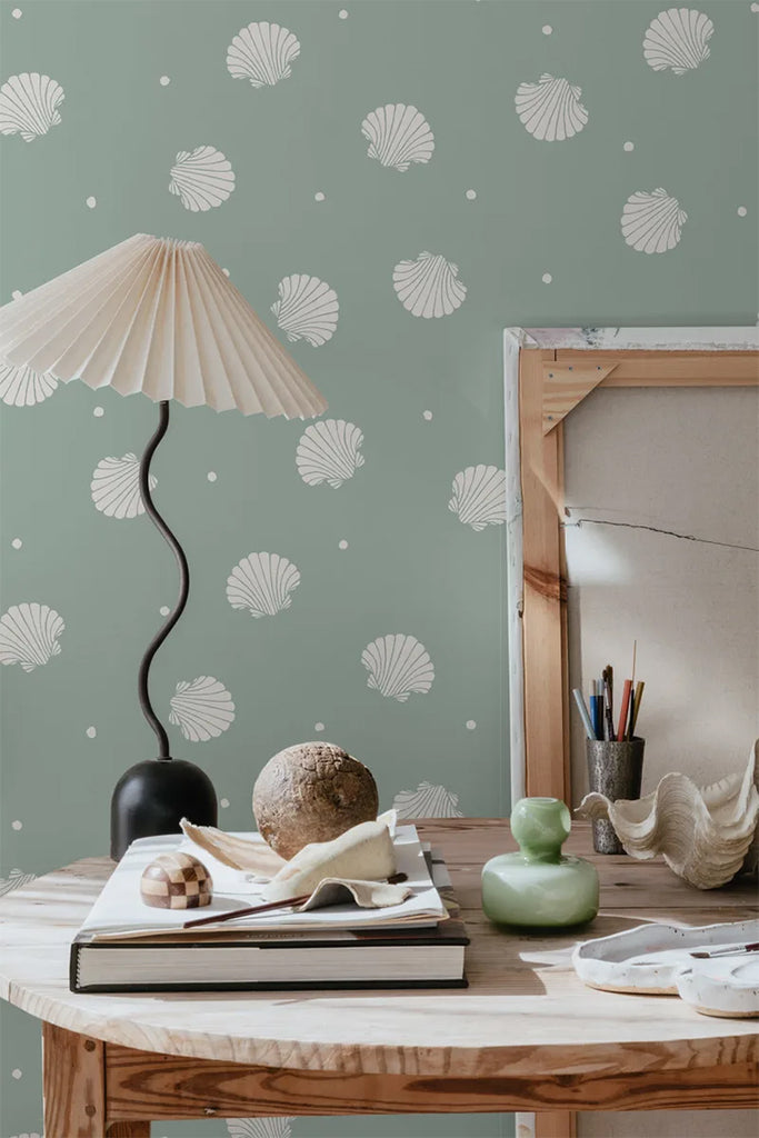 Picking Seashells, Wallpaper in Sage Featured on a wall of a round wooden table, with several items on top of it
