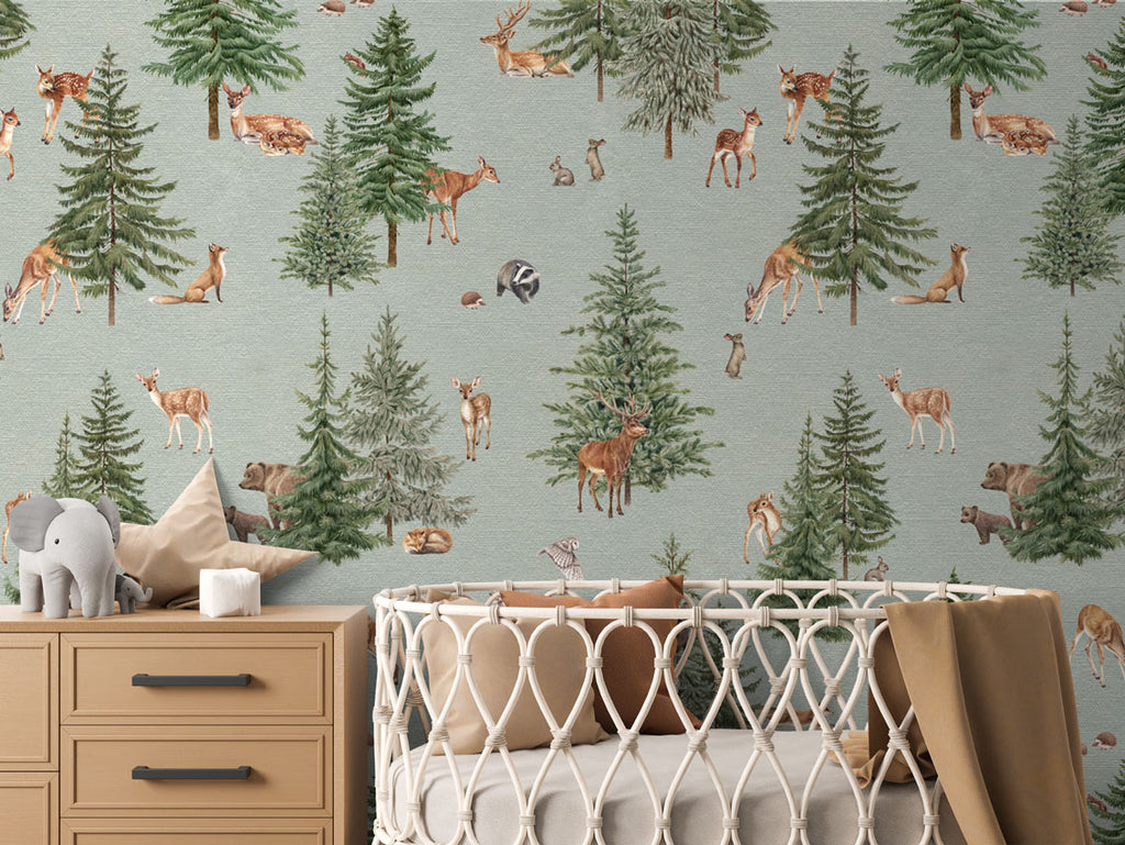 Pine forest, Pattern Wallpaper in blue colourway. The nursery room includes a wooden dresser with an elephant plush toy, and a crib with a brown blanket.