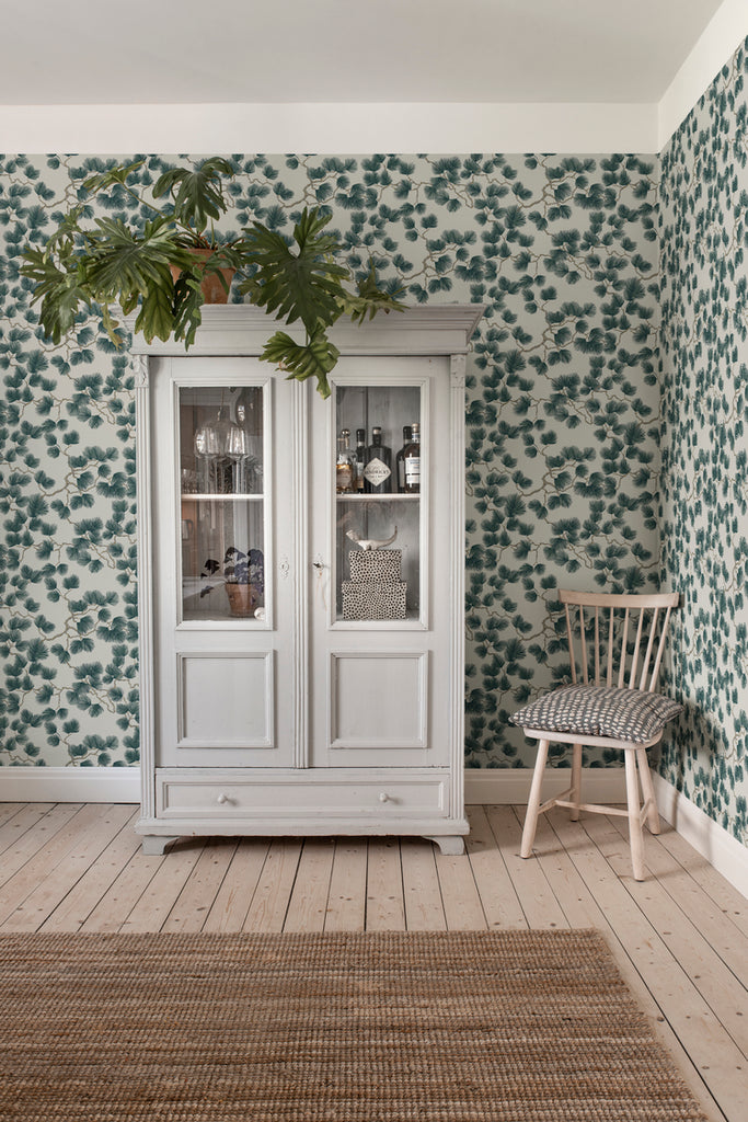 Pine, Wallpaper in green featured in a room with wooden floor and a brown floor mat with a cupboard full of kitchen wares 
