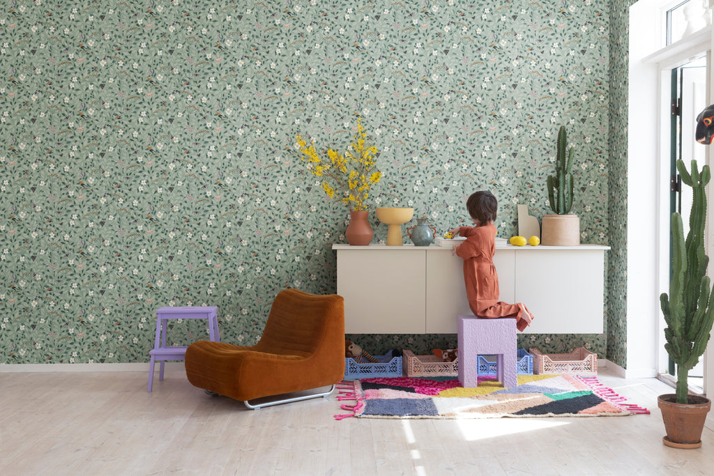 Pixie, Floral Pattern Wallpaper in Green as seen in a cozy kid’s playroom with colourful vases and toys