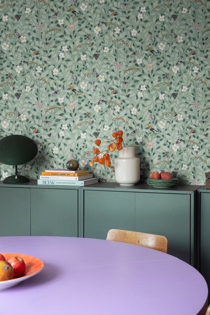 Closed up, Pixie, Floral Pattern Wallpaper featured in a dining area with a drawer full of books on top and round violet dining table.