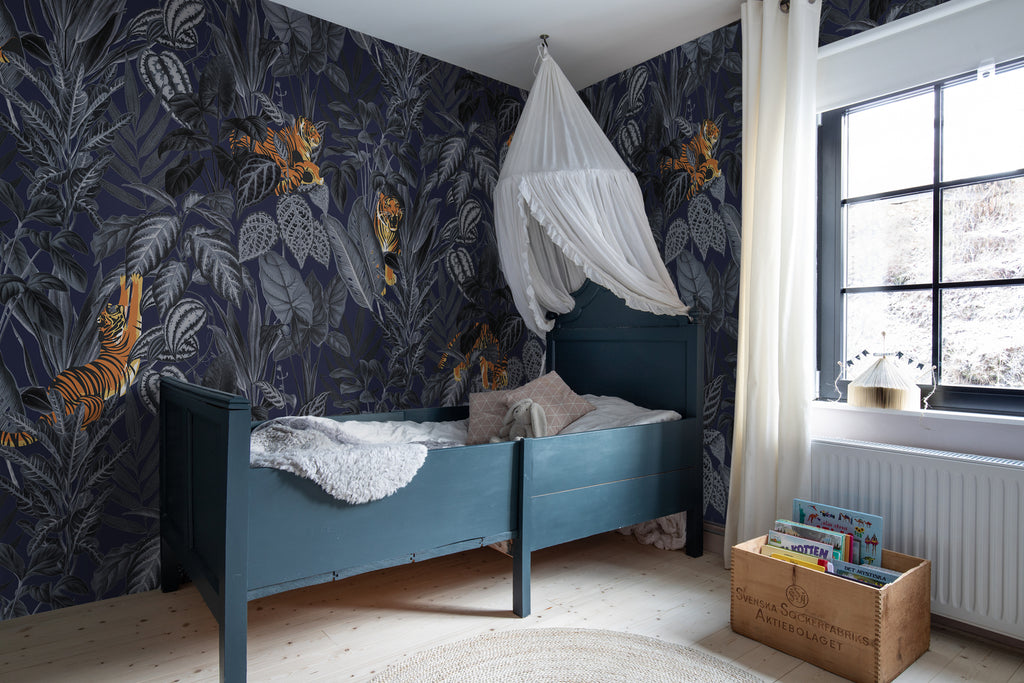 Playful Tiger, Pattern Wallpaper in dark blue colourway featured on the wall of a child’s bedroom with dark blue paint for the crib and white floating tent fabric