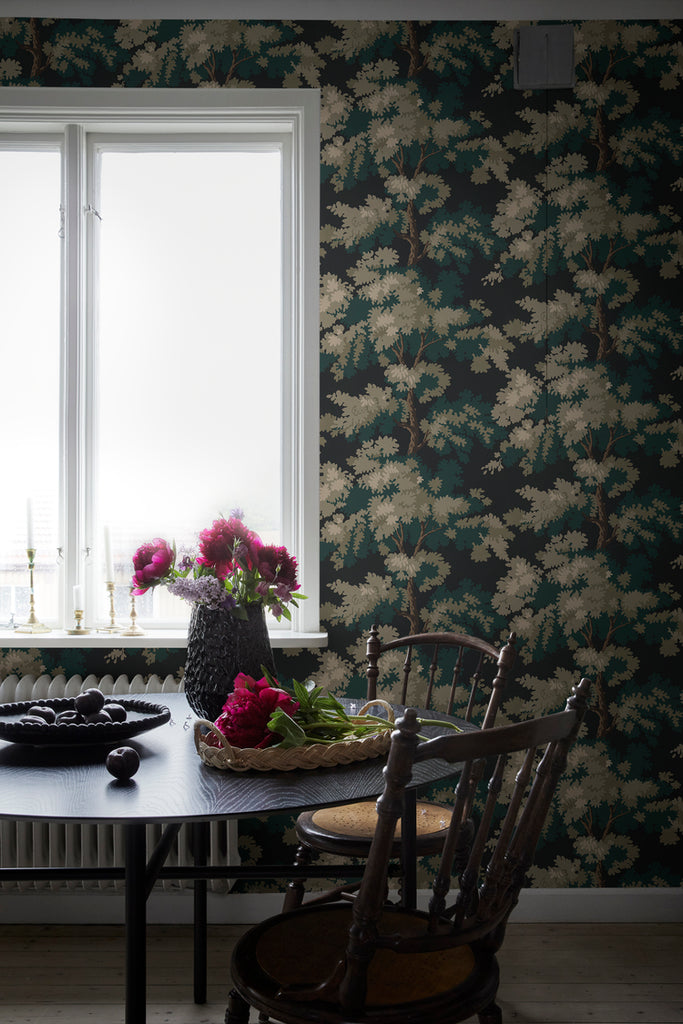Raphael Floral, Wallpaper in Dark Green featured on a wall near a window and a black table with a vase on top, and a dark brown wooden chair