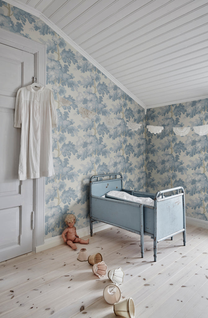 Raphael Floral, Wallpaper in Light Blue featured on a wall of a nursery room with a blue crib and several toys lined up on the floor