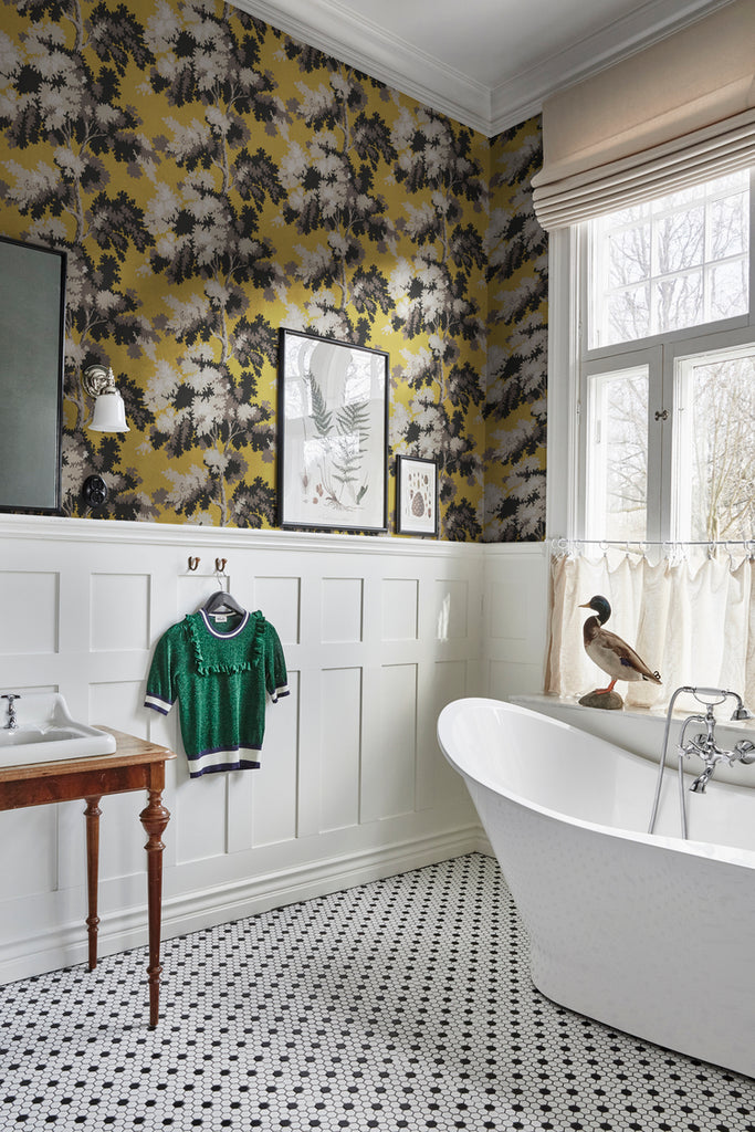 Raphael Floral, Wallpaper in Yellow featured on a wall of a bathroom, with white ceramic bath tub and a tiled flooring