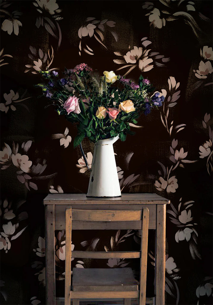 Rebecca, Floral Pattern Wallpaper in Black featured on a wall of a room with wooden chair and table, on top of it is a vase with a bouquet of flowers