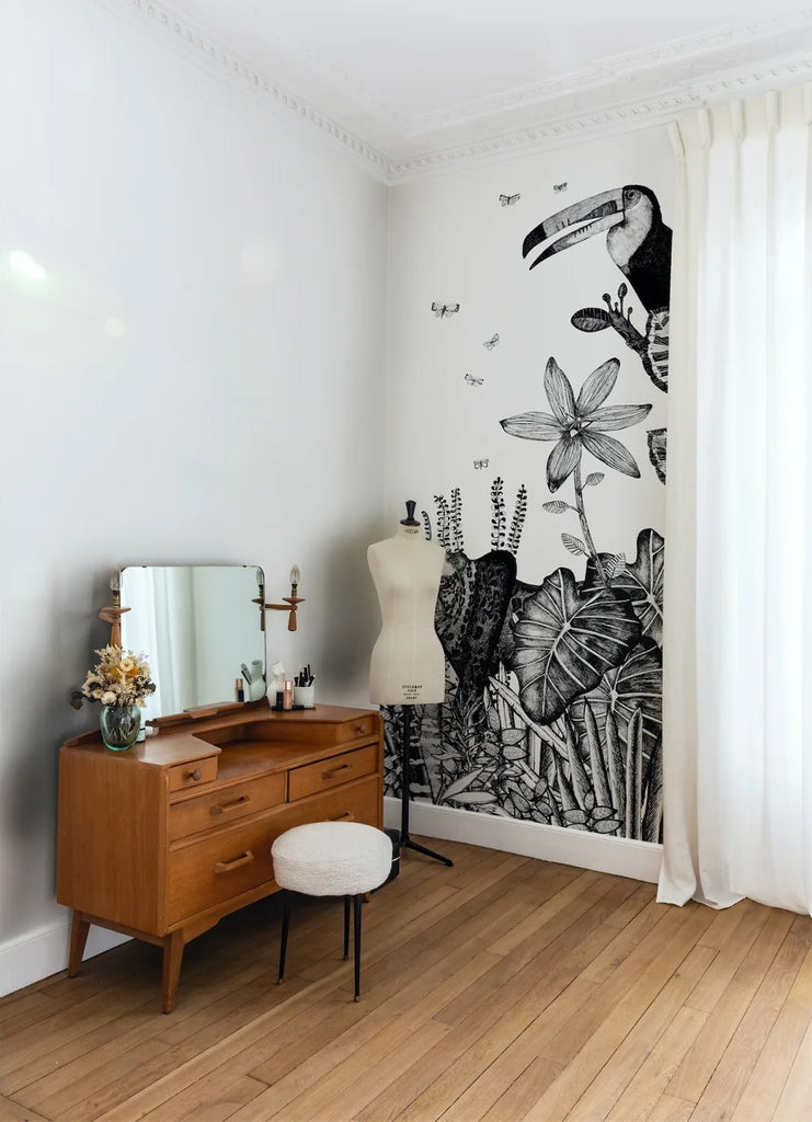 A vibrant room featuring the Safari Wild, Animal Mural Wallpaper, displaying a sketched toucan, butterflies, and tropical plants, harmoniously blending with the modern furniture.