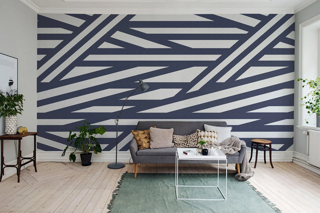 Sailor's Sea, Striped Wallpaper in Dark Blue Colourway featured on a wall of a living area with grey sofa and multicolored pillows. 