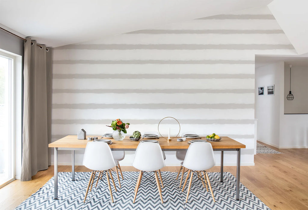Sand Lines, Striped Wallpaper featured on a wall of a dining area with wooden table and flooring, matched with white chairs, and a patterned floor mat