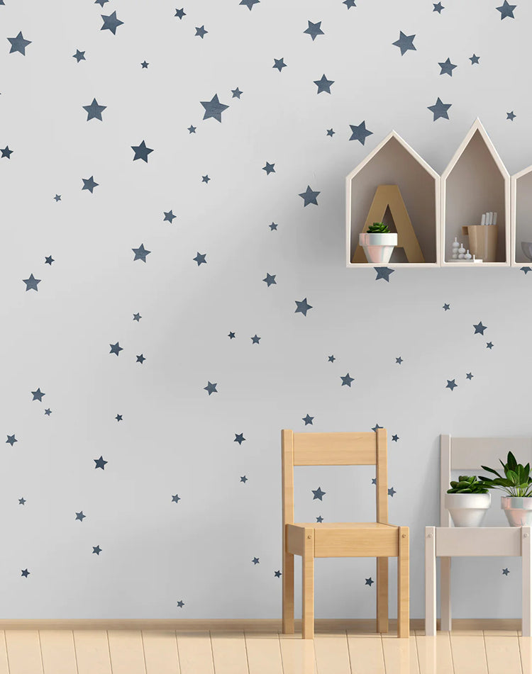 Sky Full of Stars, Pattern Wallpaper in Dark Blue, sets the tone for a room featuring a pair of mini wooden chairs and a house-shaped storage unit above.