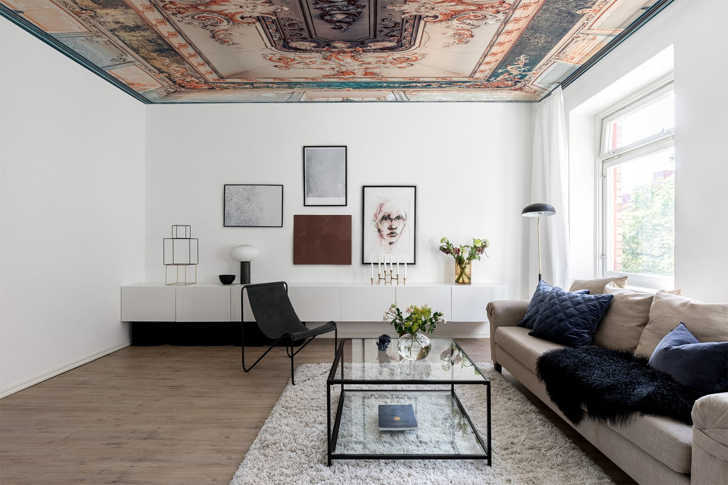 Sophie, Art Mural Wallpaper featured on a ceiling of a living area with cozy lighting and brown sofas with multiple pillows