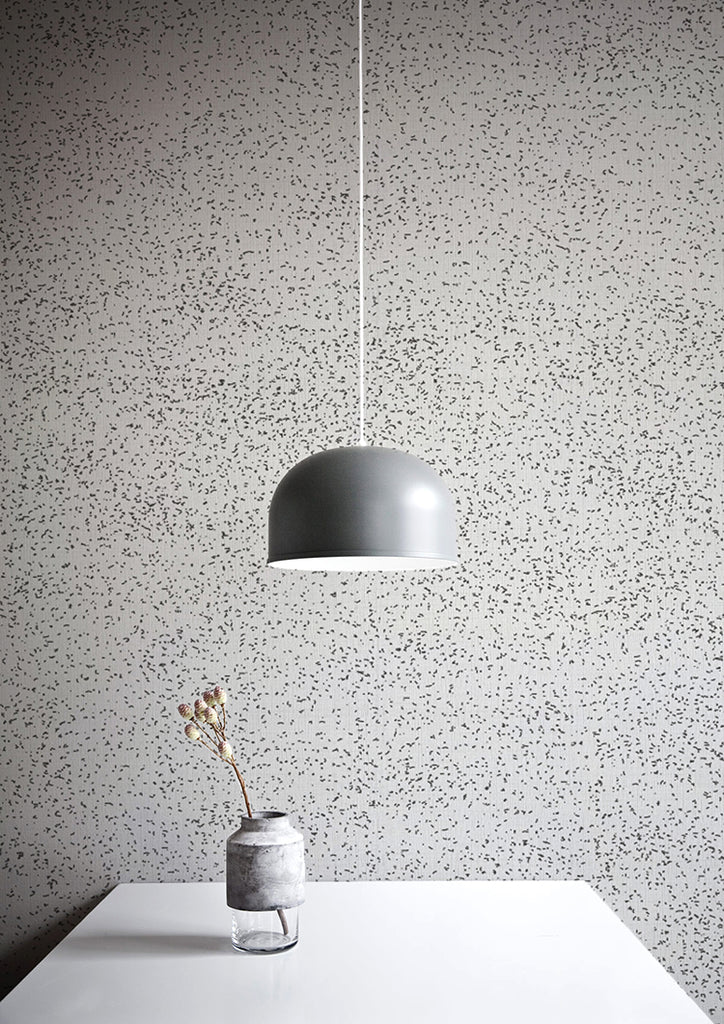 Speckle, Pattern Wallpaper in Black/White featured on a wall with white table, a vase with a plant, an a silver pendant light on top
