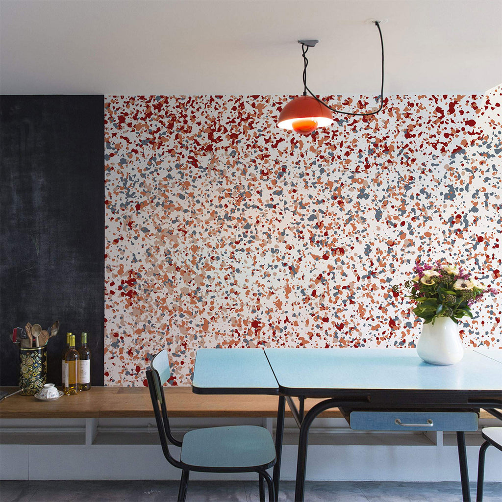 A modern dining area illuminated by ambient lighting, featuring a Stardust, Pattern Wallpaper adorned with colorful splashes, complemented by stylish furniture.