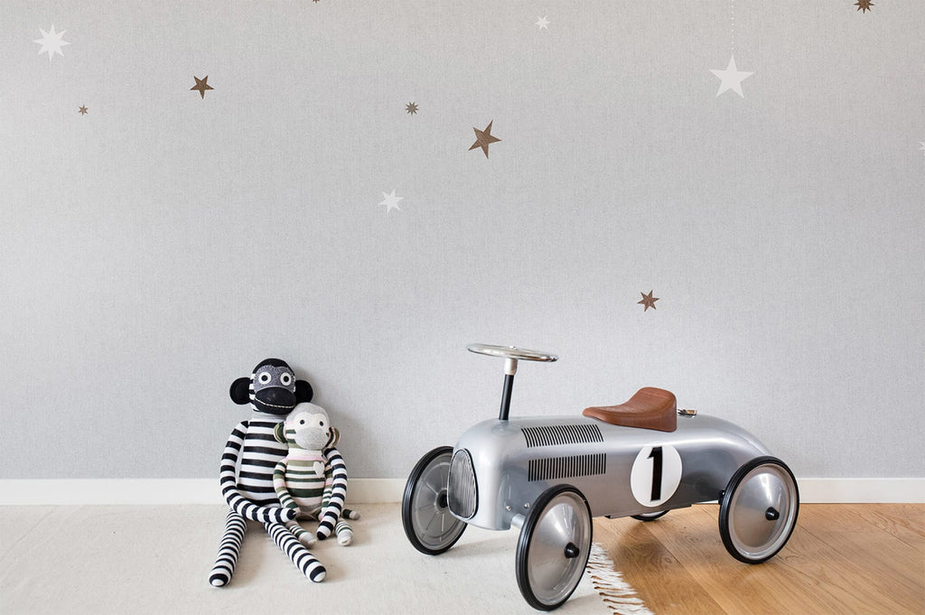 Stargazing, Pattern Wallpaper in light grey featured on a wall of a kid's playroom with monkey plush toys and silver toy car