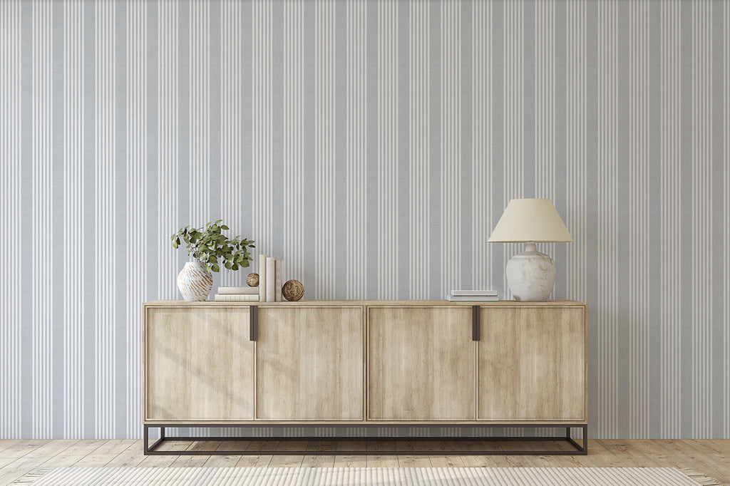 Minimalist room featuring Stripes Linen, Pattern Wallpaper in Grey Blue, a wooden sideboard with a lamp, a plant in a vase, and decorative items, creating a modern and elegant space.