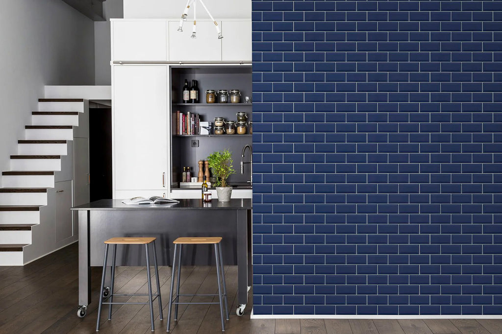 Modern kitchen with Subway Tiles, Wallpaper in Blue. Features include white cabinets, a stainless steel island, and wooden stools. A staircase on the left leads to another level.
