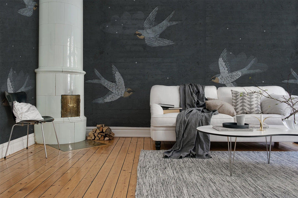 Swallow Flight, Pattern Wallpaper in dark blue featured on a wall of a living area with white sofa and grey fabrics and wooden flooring