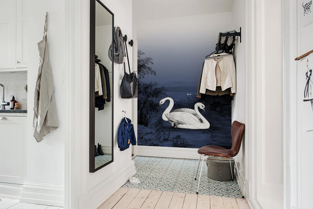 Swan Lake, Nature Mural Wallpaper in dark blue featured in wall of a foyer with several hanging clothes on the wall and light wood flooring