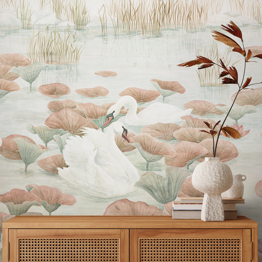 A tranquil nature scene depicted on a Swans and Lilies, Nature Mural Wallpaper in Terracotta. A wooden cabinet with books and a vase with dried plants sits against the wallpaper, enhancing the serene ambiance.