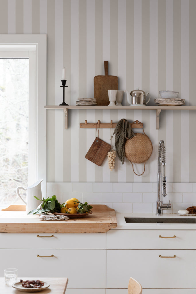 Teira Stripes, Wallpaper in Nude Featured on a wall of a kitchen area with a beautiful white accent, with its countertop having wood board on top.