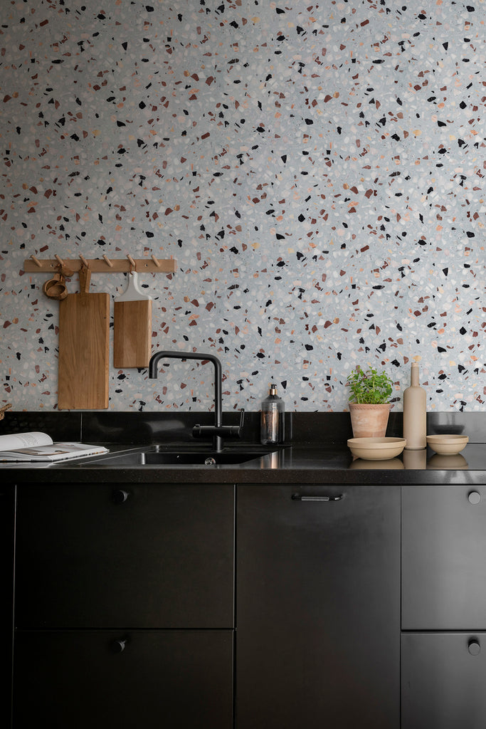 Terrazzo Kern, Faux Texture Wallpaper featured on the wall of a kitchen area, with black countertops and fixtures