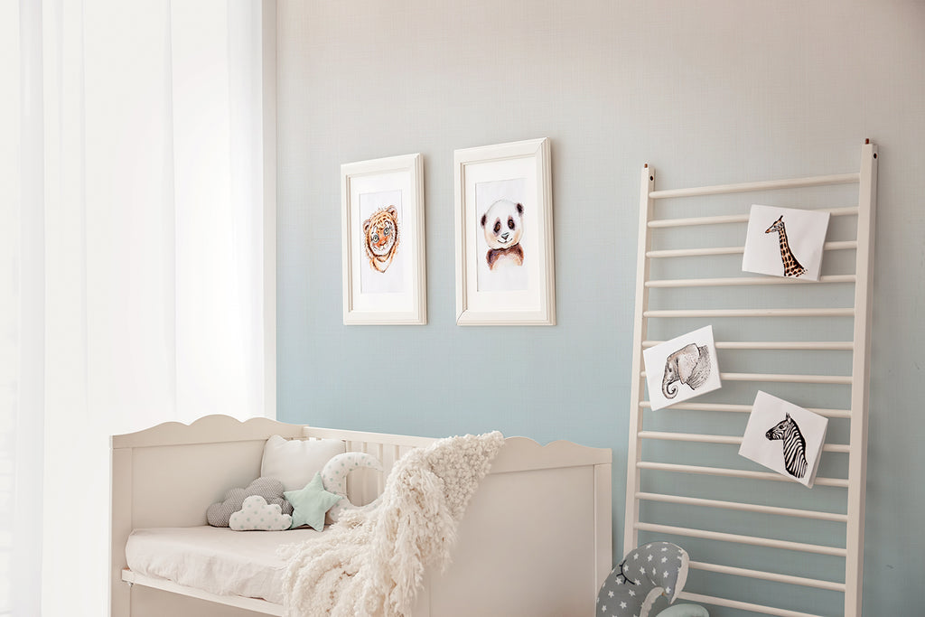 A tranquil room with Tessa, Ombre Wallpaper. The space is enhanced by a soft-hued couch with plush toys, framed animal portraits adding character to the walls, and a unique shelf displaying monochromatic art pieces, creating a harmonious and inviting atmosphere.