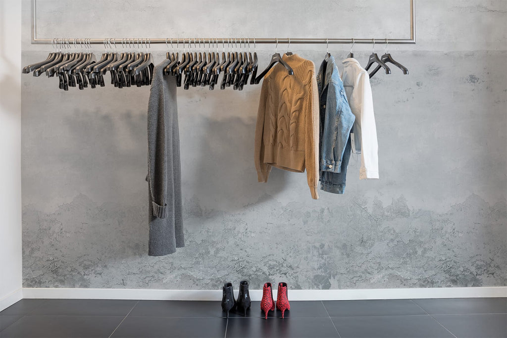The Horizon, Grey Mural Wallpaper sets the scene in a room where clothes hang, creating a stylish and inspiring atmosphere.