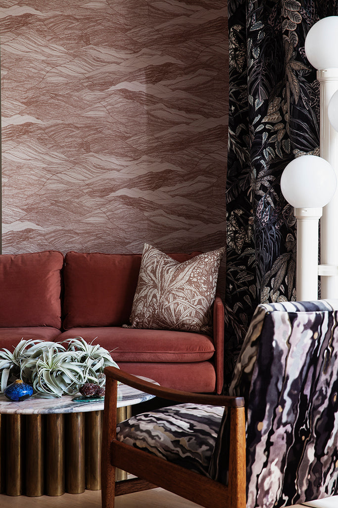 Tidal Waves Wallpaper in Terracotta graces a living area where it is complemented by black curtains and a stylish black foamed wooden chair, resulting in a bold and sophisticated interior.