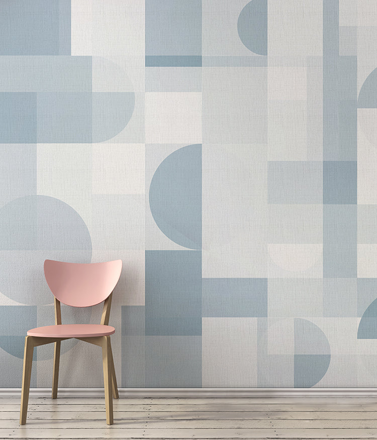 The room features a wall adorned with Tribe Geometric Wallpaper, in Blue, complemented by a pink chair on wooden flooring