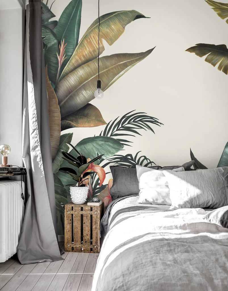 The Tropical Forest Mural Wallpaper, in multicolor, graces the bedroom wall. The room features a grey bed with multiple pillows and a side table holding a potted plant.